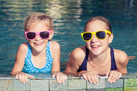 两个快乐的孩子们在一天时间在游泳池里玩