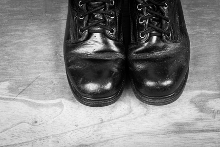 老黑作战靴上木制的背景，黑白色调