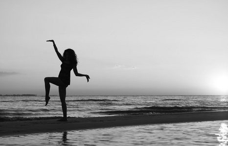 在日落时分做体操在海滩上的女孩