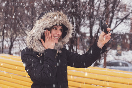 女人做在冬季公园自拍照
