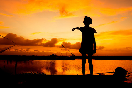 可爱的小女孩玩在河日落背景