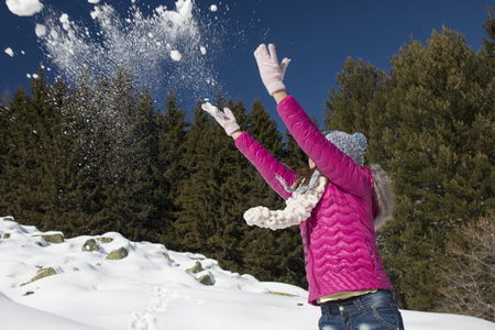 一个年轻的姑娘在冬天玩雪