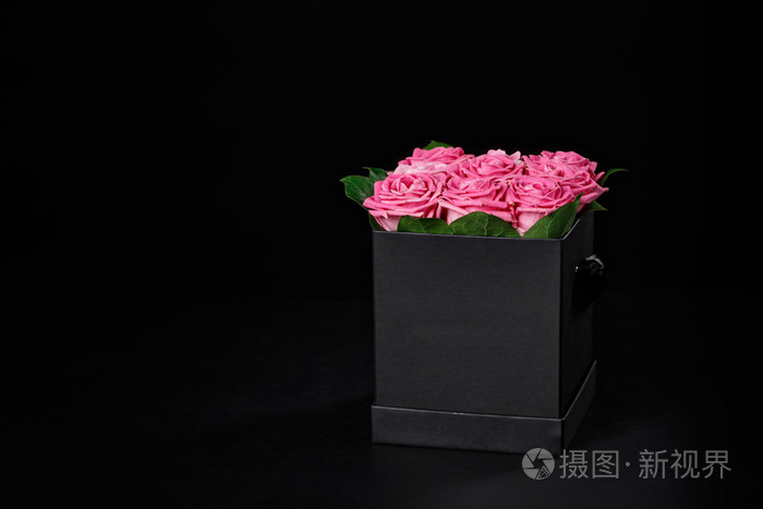 粉红色的玫瑰花放在黑色背景的方形小黑礼盒里