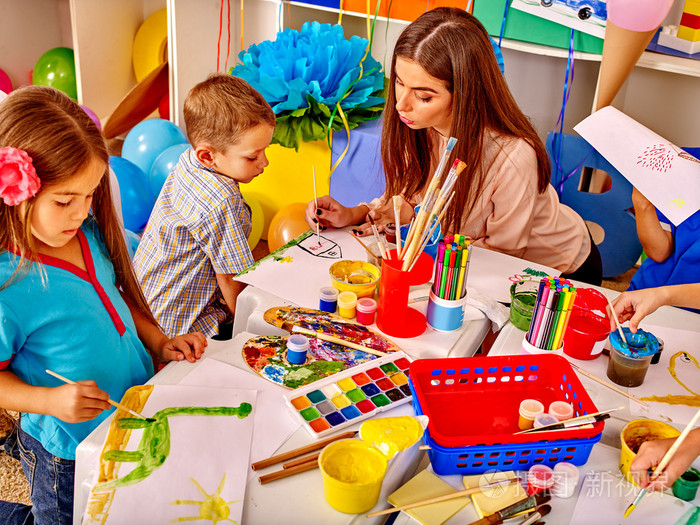 孩子们在幼儿园用老师的女人在纸上画画