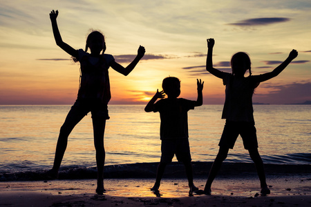快乐的孩子们在日落的时候在海滩上玩