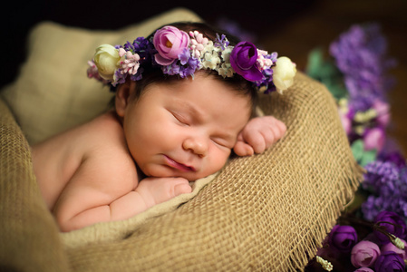 紫色的花环美丽新生女婴睡在一个柳条篮子