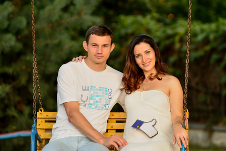快乐怀孕的夫妻坐在公园里下属
