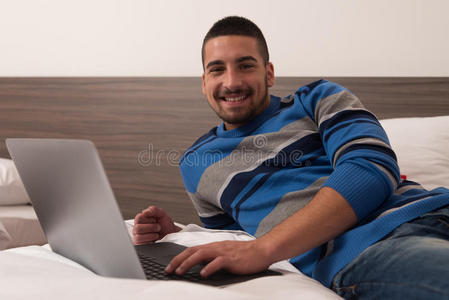 微笑的年轻学生在床上用笔记本电脑