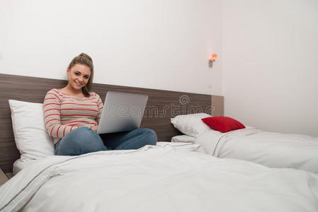 快乐的年轻女人在床上用笔记本电脑