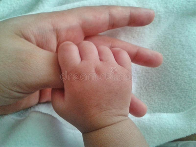 抱着母亲拇指的婴儿