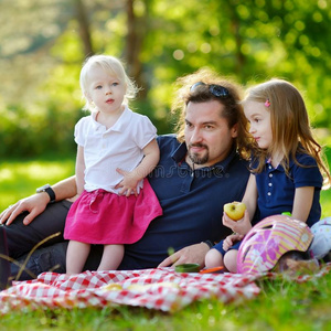 年轻的父亲和他的女儿们正在野餐