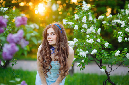 美丽的女人在一个郁郁葱葱的花园里，春天的紫丁香