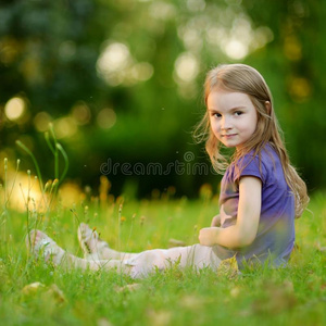 可爱的小女孩坐在草地上