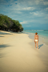 沿着热带海滩散步的年轻女子