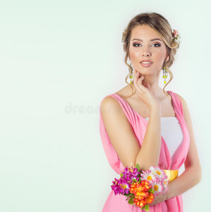 美丽的女孩子就像一个新娘，她的化妆发型很亮，头上戴着粉红色的连衣裙，头上戴着鲜花玫瑰