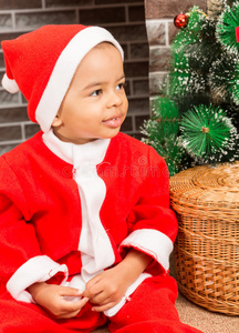 非洲裔美国男孩在壁炉旁给圣诞老人穿上服装。