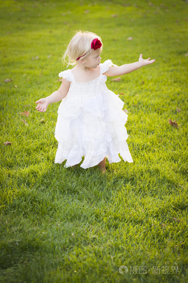 可爱的小女孩穿着白色连衣裙在草地上