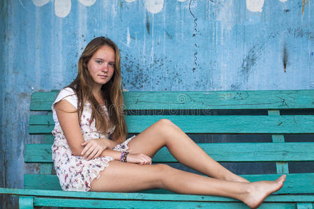 坐在长凳上的女孩，背景上的旧脏墙。