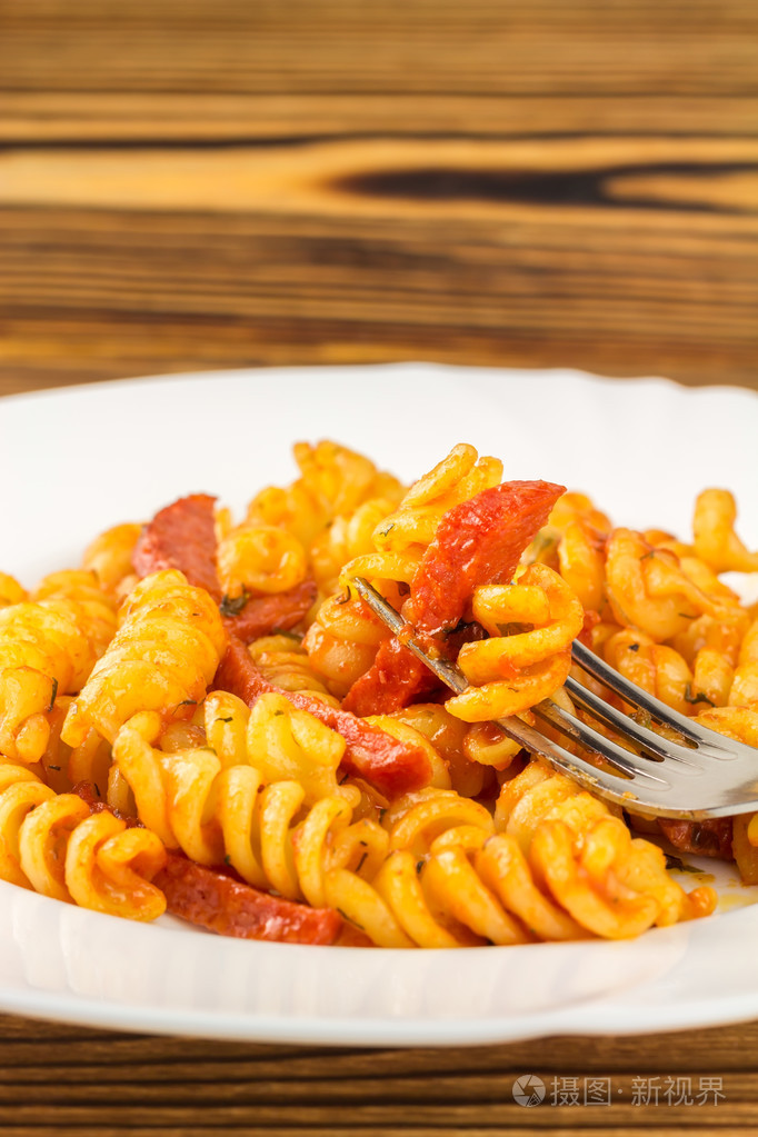 italian pasta fusilli with tomato sauce and sausage skewered on
