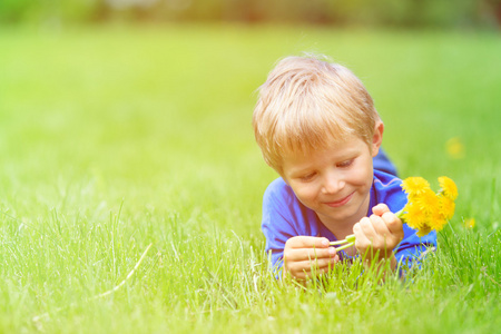 可爱的快乐小男孩躺在绿草上春天