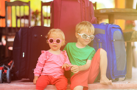 小男孩和蹒跚学步的女孩坐在行李箱准备旅行