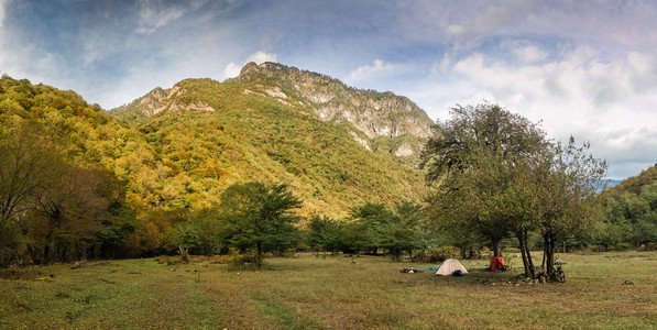 在一片空地上一棵树上高山树木繁茂的背景下的旅游营地