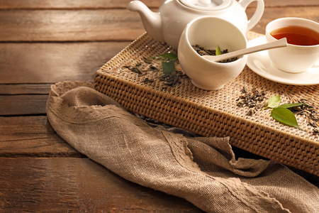 绿色的叶子中套茶具上木桌特写茶颗粒