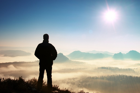 边缘的口袋里男人站在悬崖上的砂岩岩石和迷雾笼罩的山谷到太阳美丽