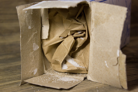 牛皮纸盒小食盐洒到木制的背景图片