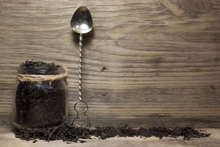 干茶叶红茶和玻璃罐木制背景上。文本的空间