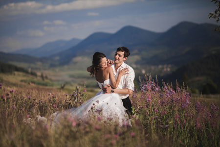 浪漫的童话夫妇新婚夫妇接吻和拥抱，背景为山