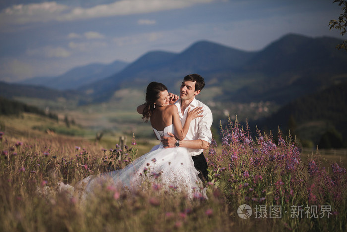 浪漫的童话夫妇新婚夫妇接吻和拥抱,背景为山
