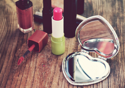 可爱小口袋镜子中用粉色口红或其他化妆品木制的桌子上心的形状