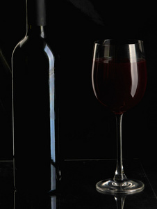 优雅的红酒杯和酒瓶在黑色的背景