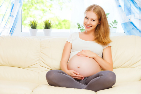 快乐的孕妇在家休息，坐在沙发上