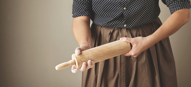 女人抱着木擀面杖在手里揉面粉