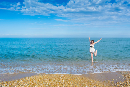 快乐的年轻女人在海滩上跳跃