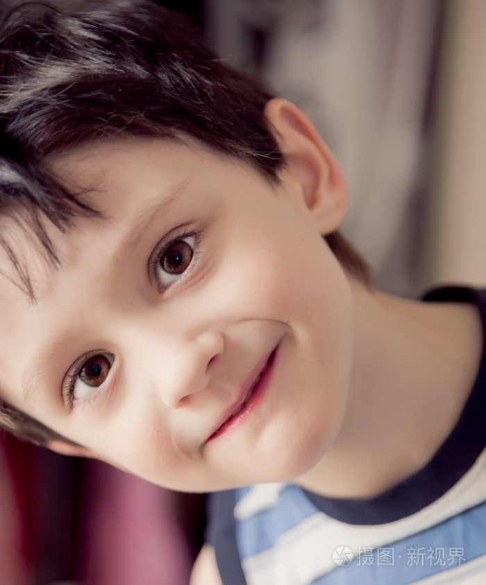 小的黑发男孩身穿条纹的衬衫室内