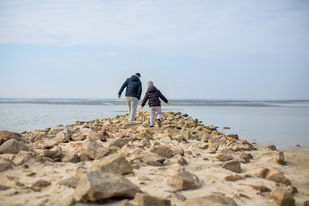 父亲和儿子在沙滩上漫步的岩石