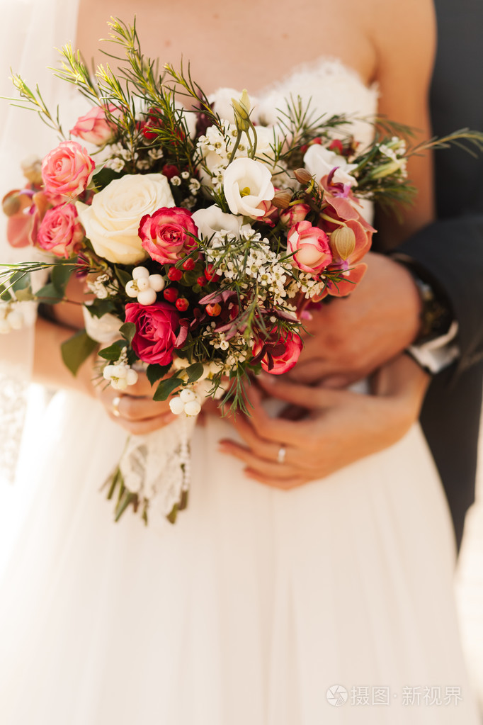 新郎新娘抱着玫瑰花束