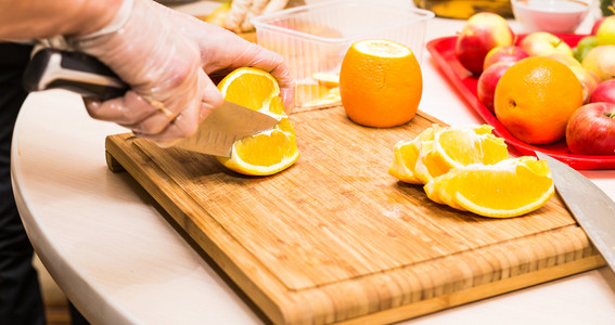 年轻干净的厨师手切橘子在桌子上