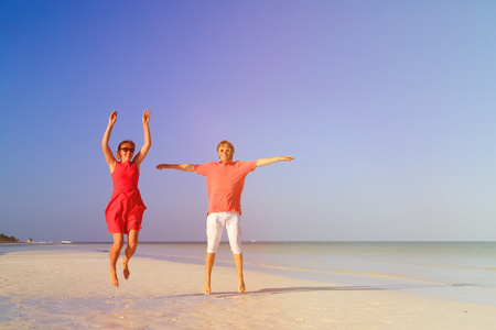 幸福的夫妇在夏天海滩上跳跃