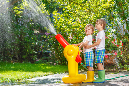 两个小孩子玩的橡胶软管和水在夏天