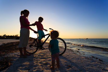 母亲带着两个孩子骑自行车在日落时分