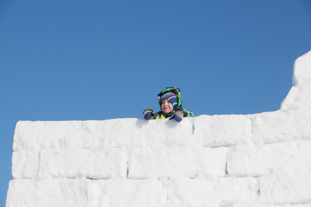 快乐的孩子，在从雪块墙顶部的颜色夹克