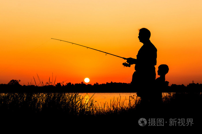 父亲和儿子在河日落背景钓鱼