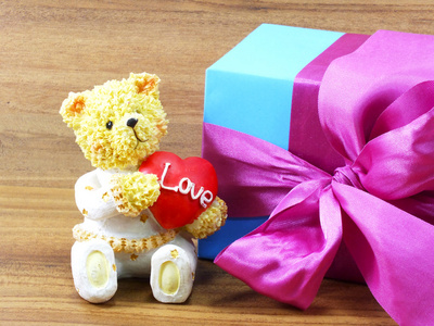 玩具熊坐在红色的心和圣诞礼品盒包纸