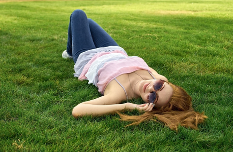 幸福的女人，戴着眼镜躺在草地上