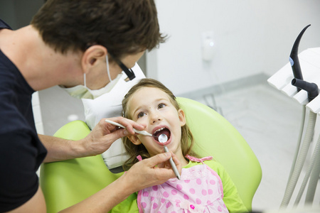 女孩坐在牙医的椅子上她定期牙科检查