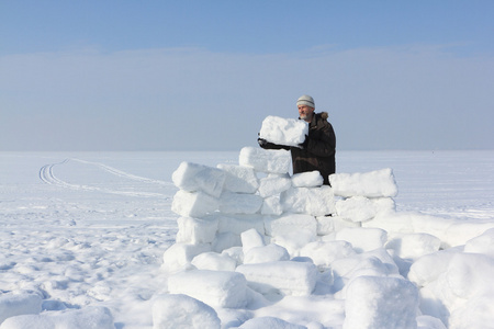 在冬天建设一座冰屋的林间空地上的雪块留胡子的人